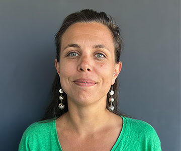 Photo de Julie H, graphiste et communicante, sur fond gris, portant un t-shirt vert pomme.