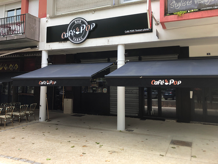 Enseigne lumineuse du Café Pop sur bandeau noir avec le logo et la baseline, vue extérieure du bar tabac à Lorient