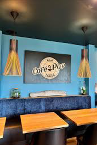 Logo du Café Pop en découpe bois sur fond noir, installé à l’intérieur du bar, reflétant l’identité visuelle chaleureuse et moderne