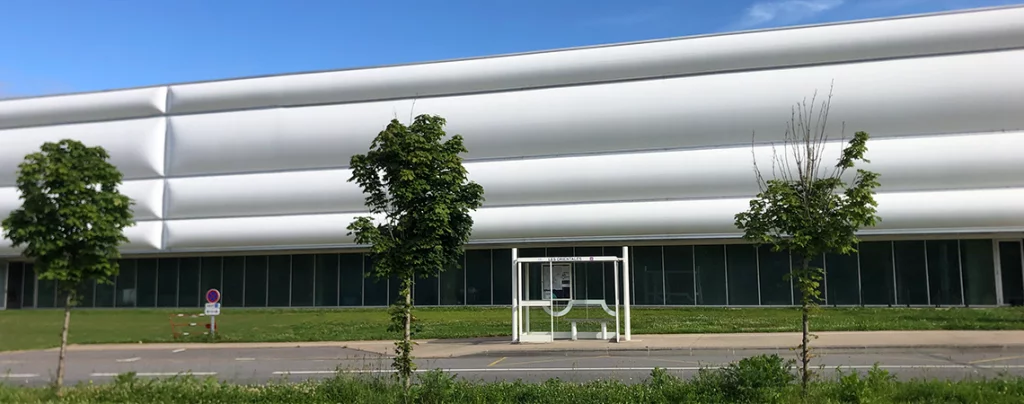Bâtiment du Hennebont Ping Center montrant les baies vitrées à habiller, l’éloignement de la route et la forme du bâtiment