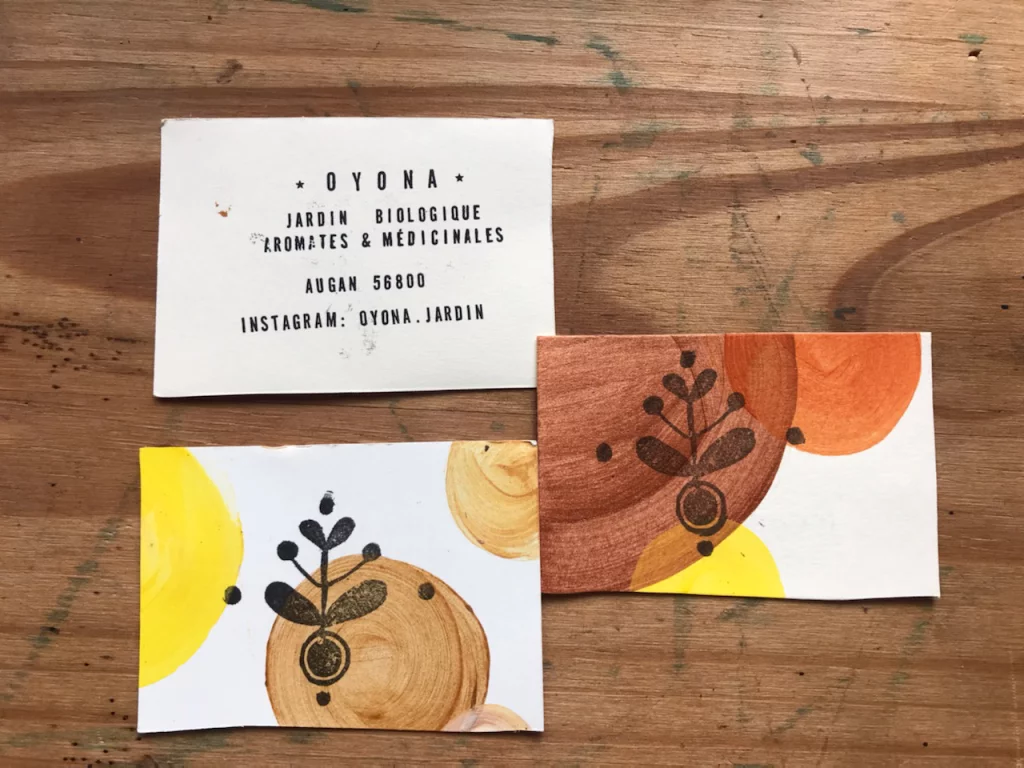 Carte de visite artisanale Oyona, recto et verso, rond de peinture jaune/orangé et tampon végétal noir sur papier découpé à la main
