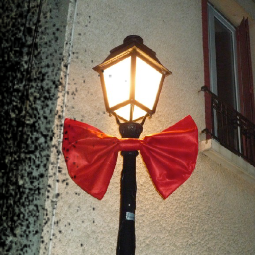 Lampadaire parisien décoré d’un nœud papillon rouge dans le cadre du street marketing de Noël pour Nose