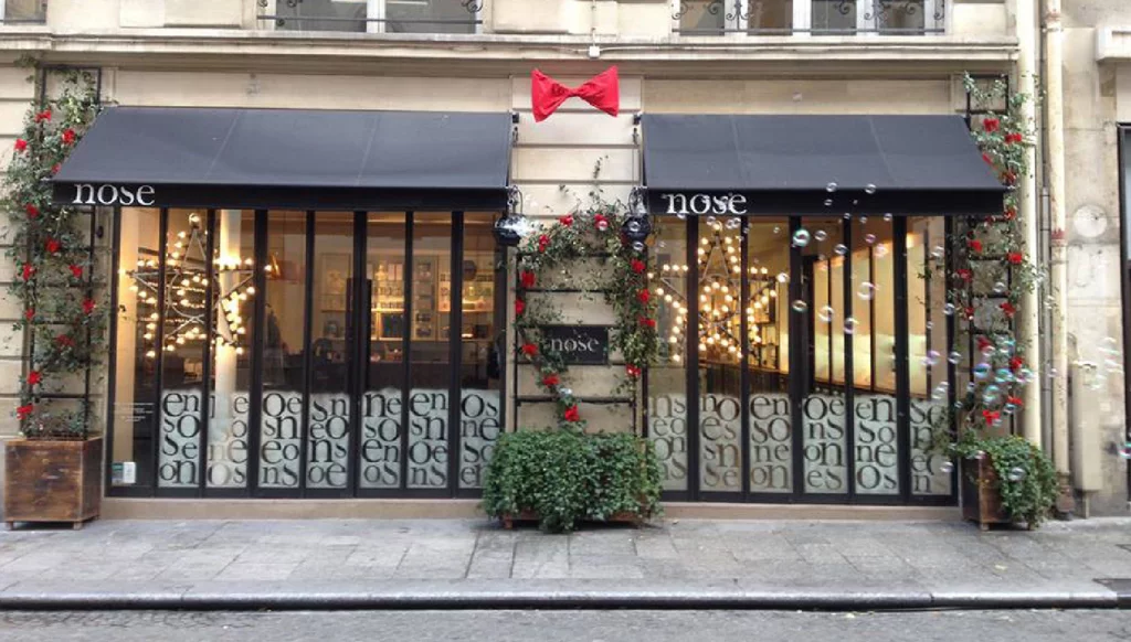 Façade de la boutique Nose décorée pour Noël avec nœuds papillon rouges et neige sur les vitres